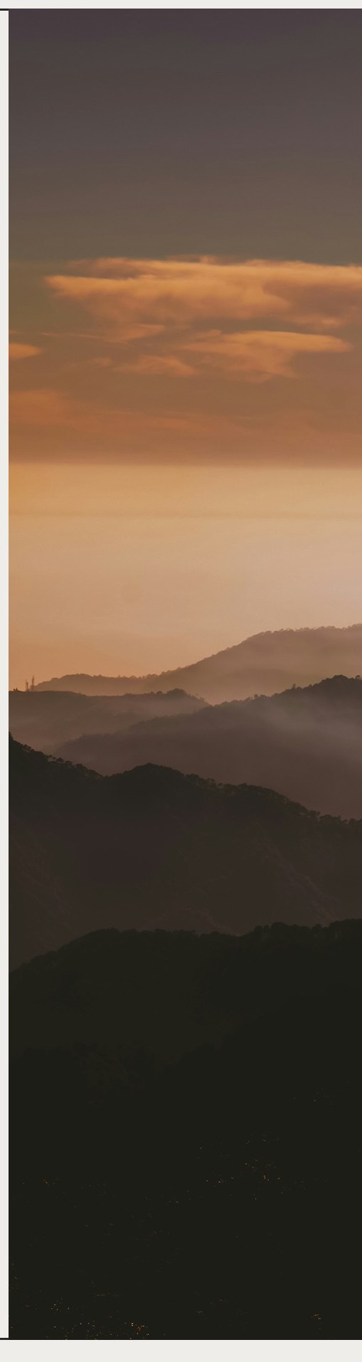 Mist drifting over forested mountains at dawn