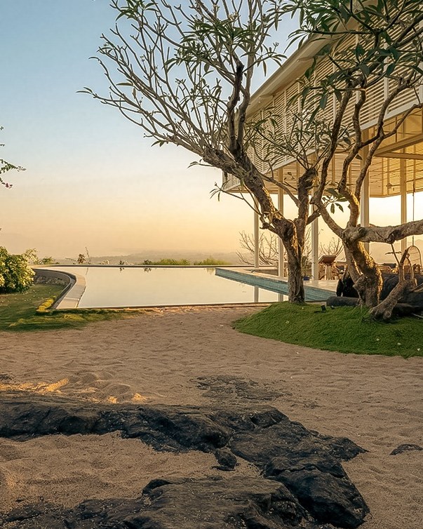 Pathway to a pavilion beside still water at sunset